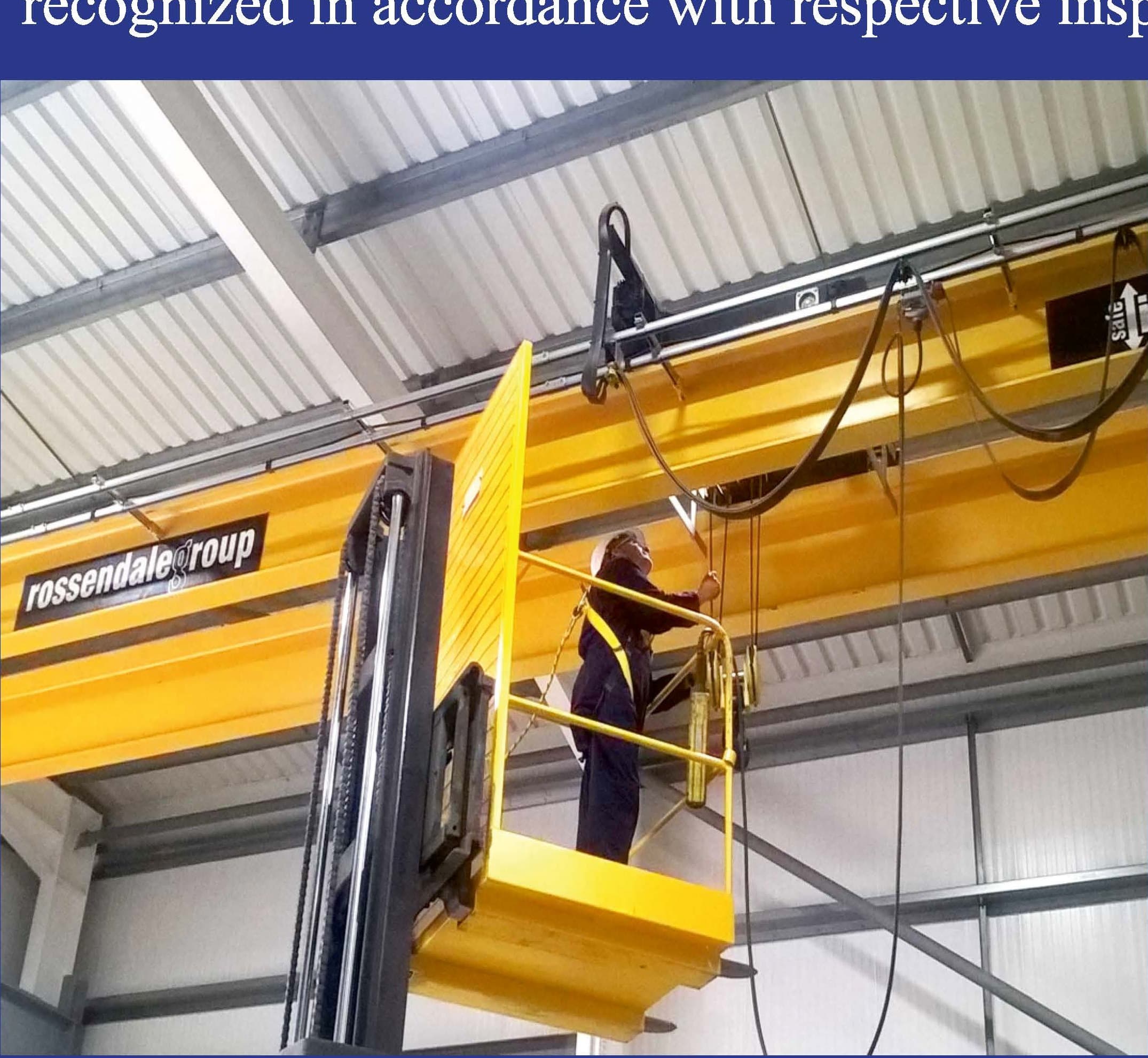 A technician on an elevated platform inspecting an overhead gantry crane.